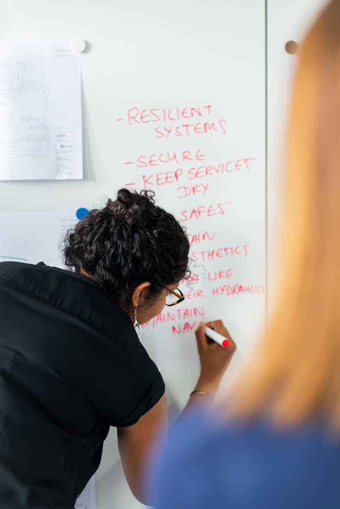 services-01 Female engineer writing strategy on a whiteboard during a business meeting.